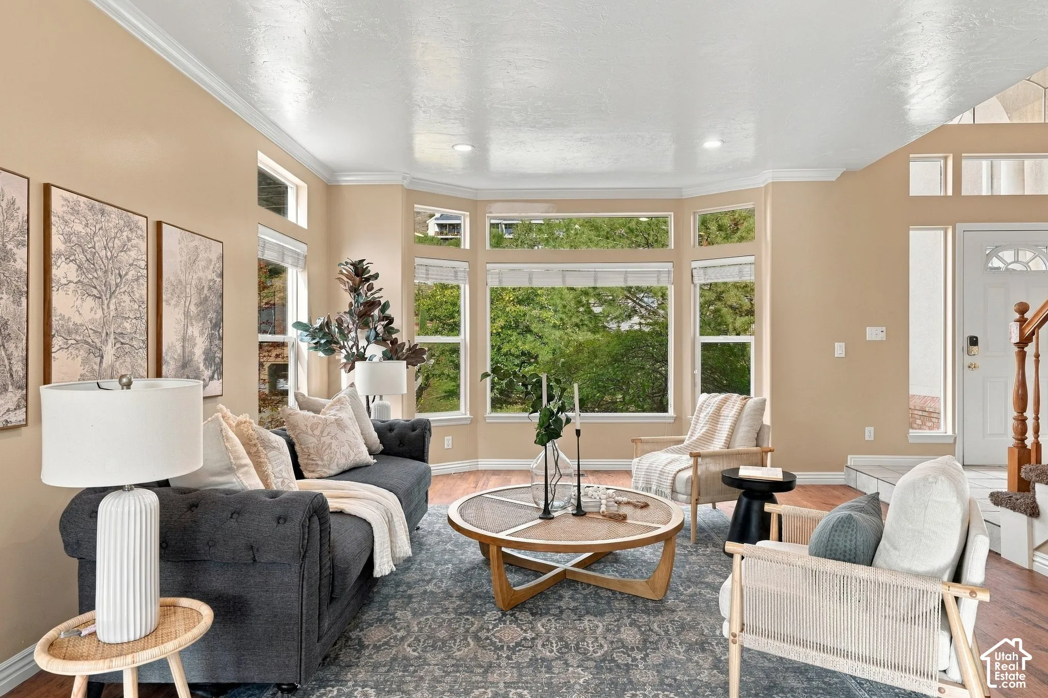 Living area featuring a bay window, wood-finish flooring, vaulted ceilings, recessed lighting, and a staircase with a wooden banister