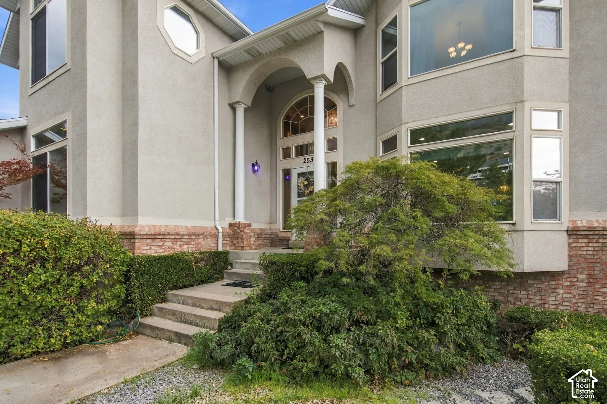 Multi-level exterior featuring a brick and stucco facade, arched entryway with decorative columns, and multi-pane windows