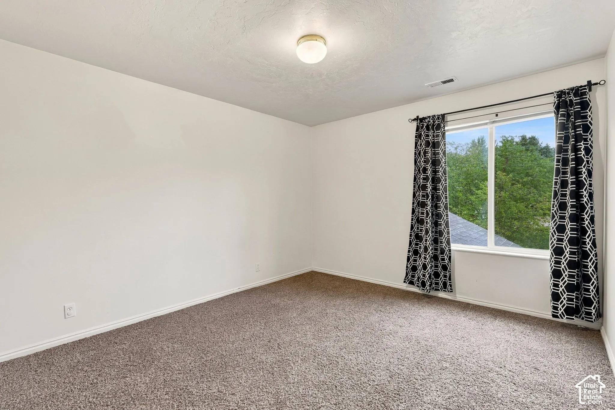 Neutral-toned carpeted flooring, white walls, and a window providing exterior greenery