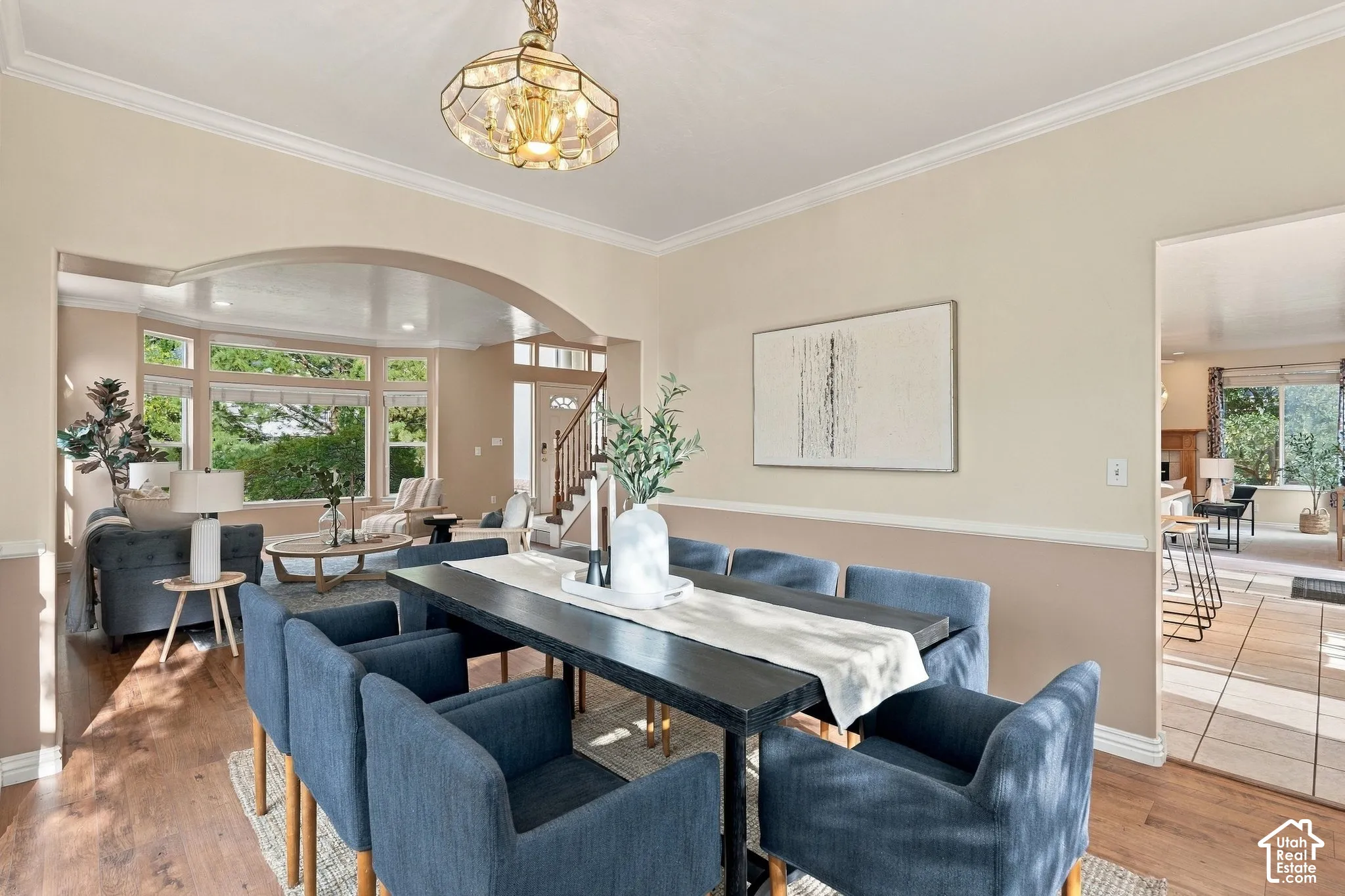 Dining area featuring wood-finish flooring, a decorative pendant light fixture, arched architectural detailing, and crown molding