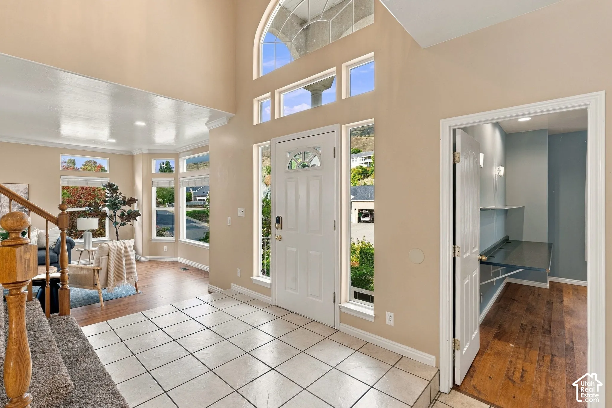 Entryway featuring a double-height ceiling, arched window, tile flooring, wood-finish flooring, and a built-in workspace