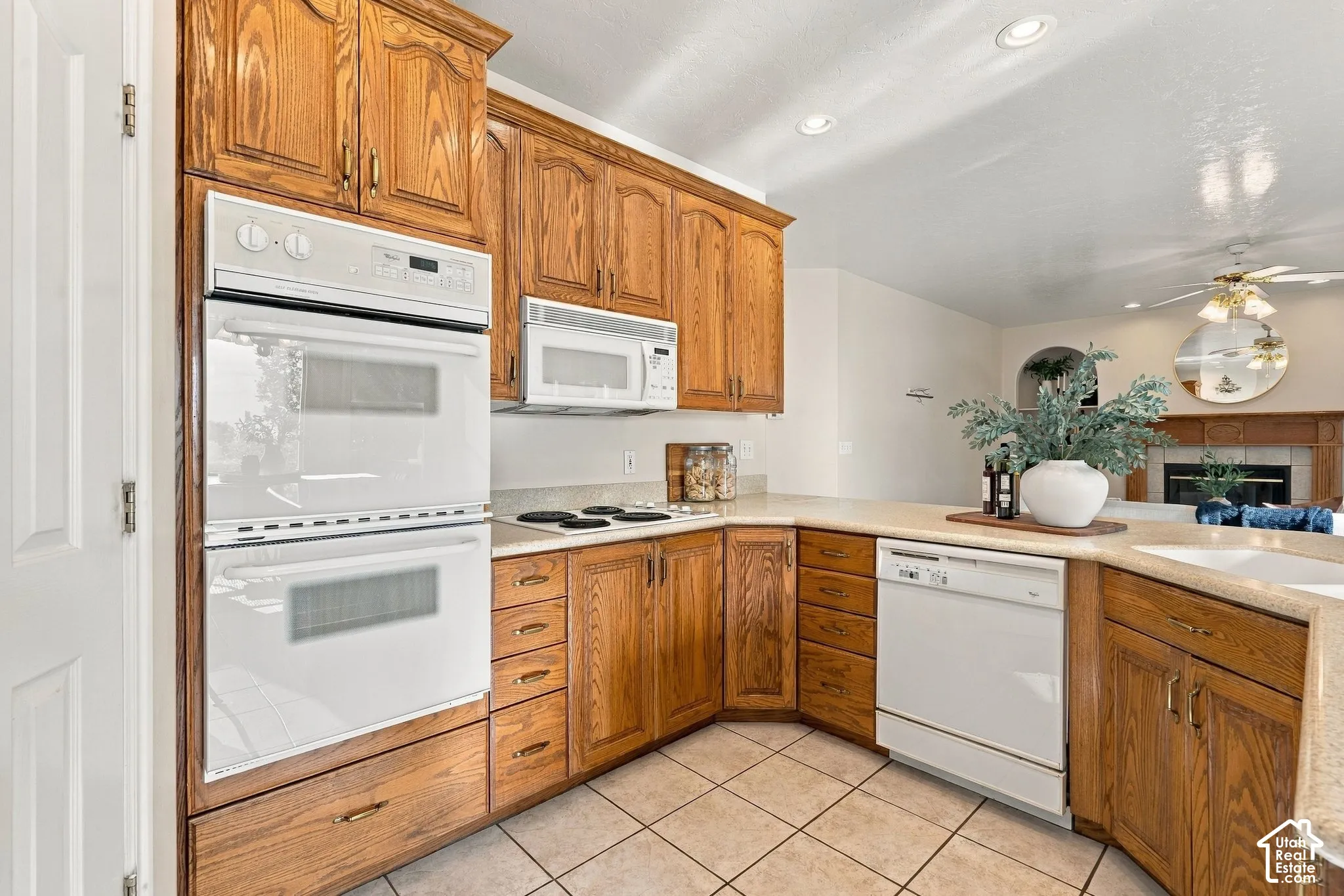 Kitchen featuring solid wood cabinetry, built-in double ovens, electric cooktop, white appliances, and tiled flooring