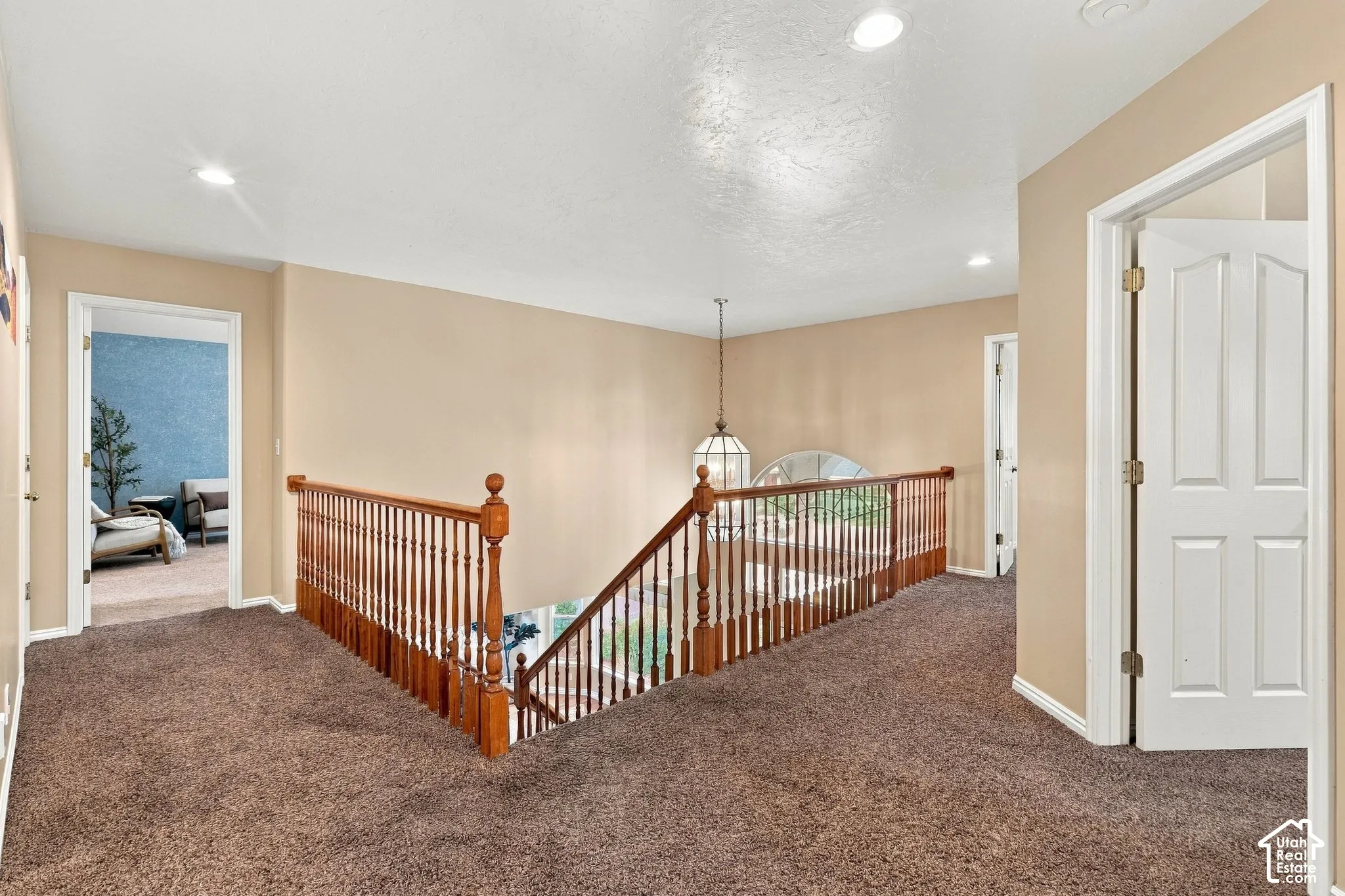Open floor space featuring recessed lighting, a wooden handrail with balusters, and multiple interior paneled doors
