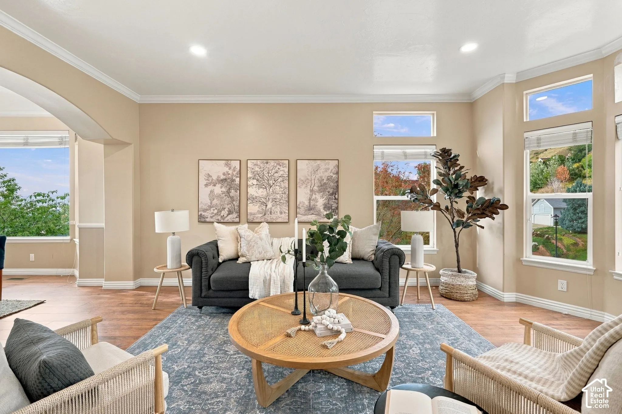 Living area featuring wood-finish flooring, recessed lighting, crown molding, and large windows with natural scenery