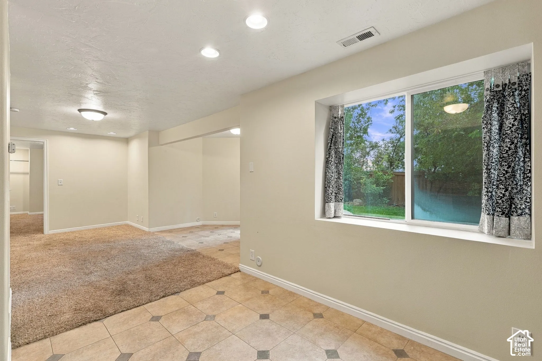 Interior space featuring recessed lighting, large picture window, neutral wall paint, and combination of tiled and carpeted flooring