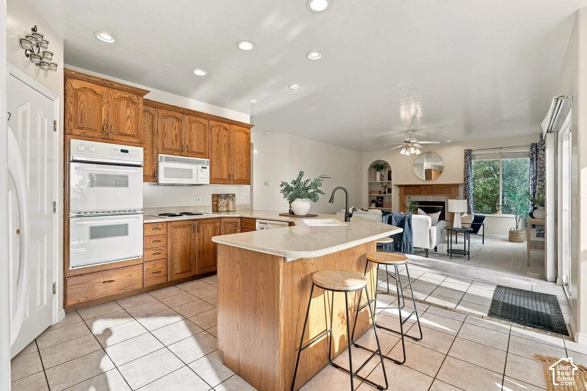 Kitchen featuring wood cabinetry, stone-finish countertops, an integrated double wall oven, a central island with a sink, and recessed lighting