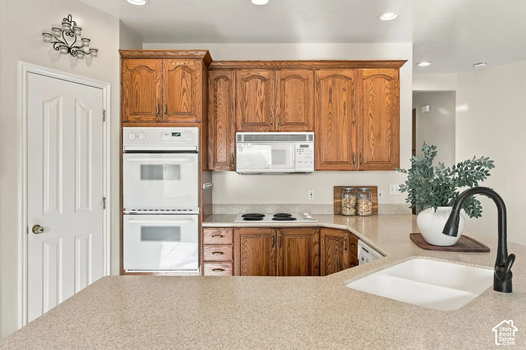 Kitchen featuring wood cabinetry, integrated double wall ovens, built-in microwave, solid surface countertops, and a dual-basin sink with a matte black faucet
