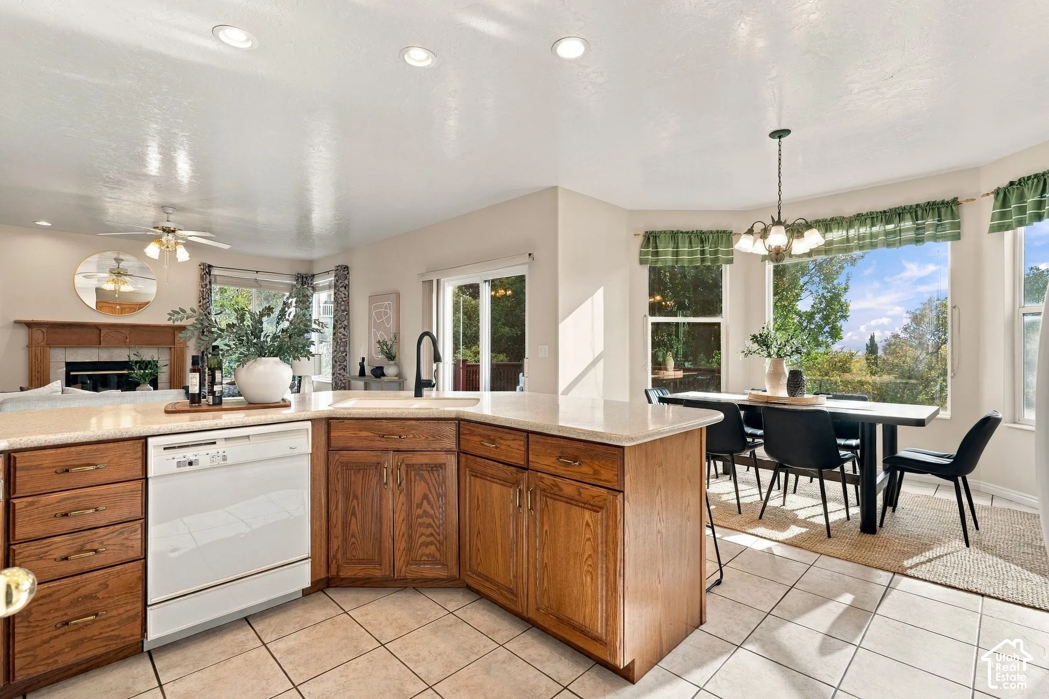 Kitchen featuring a central island with a solid-surface countertop, cabinetry with a natural wood finish, a tile floor, recessed lighting, and a bay window
