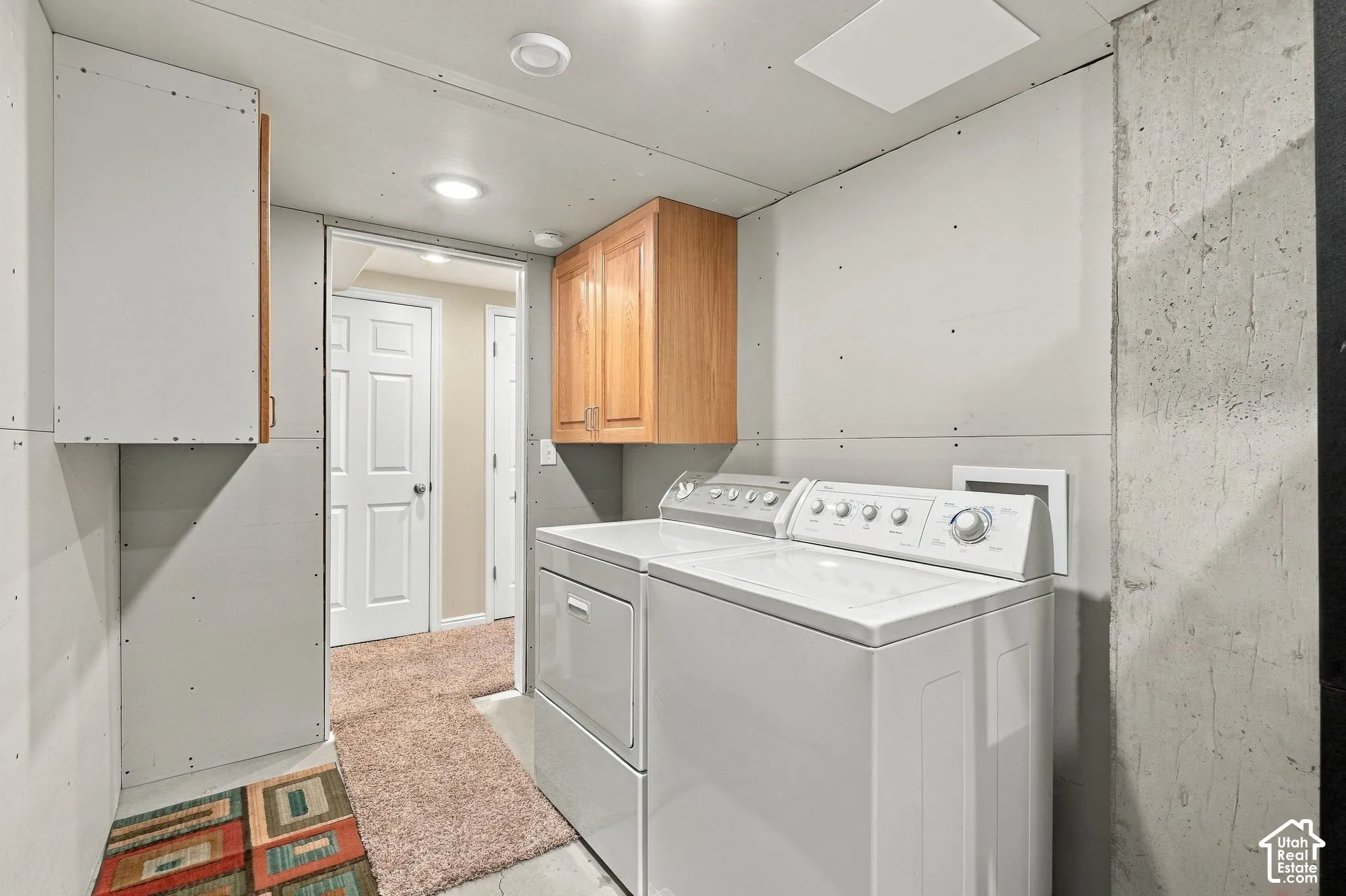 Laundry area featuring recessed lighting, wall-mounted wood cabinetry, and drywall finish