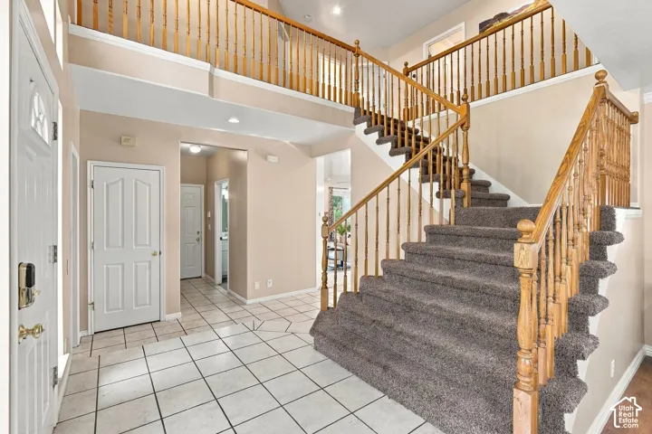 Grand foyer featuring soaring ceilings, ceramic tile flooring, and a sweeping staircase with wooden balusters and carpeting