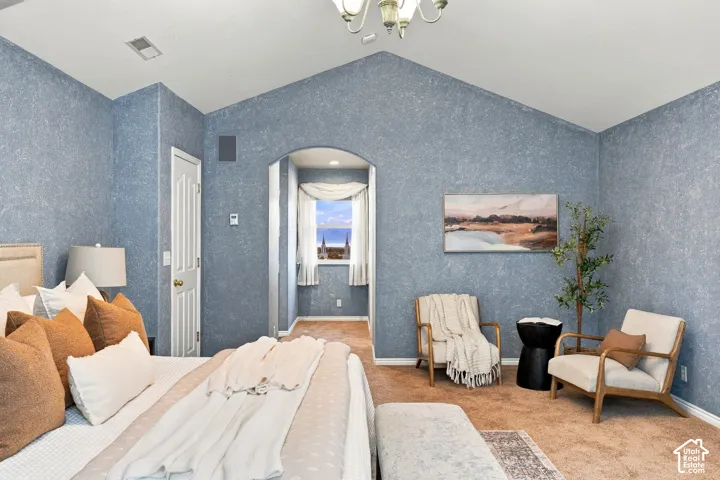 Vaulted ceilings with a multi-arm chandelier, textured wall finish, and an arched entryway leading to a windowed alcove