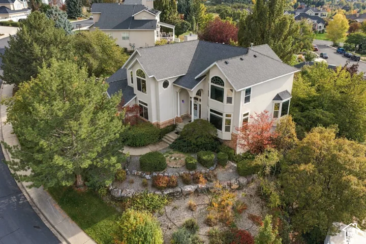 Multi-level residence featuring a textured exterior facade, shingled roof, arched windows, and multi-tiered landscape terracing with stone retaining walls