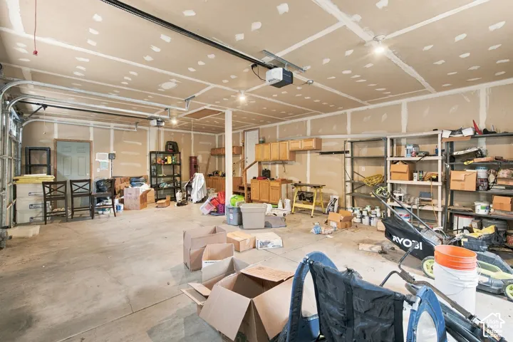 Multi-car garage featuring a concrete floor, built-in wooden cabinetry, recessed lighting, and an automatic door opener