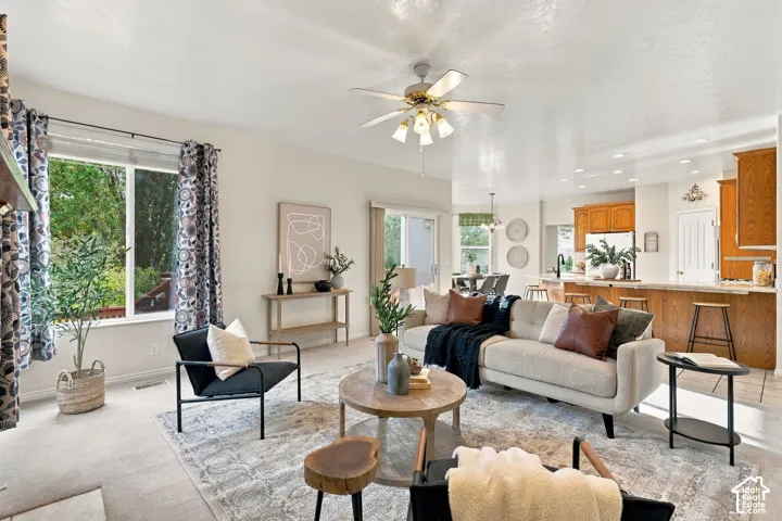 Open-concept interior featuring recessed lighting, a ceiling fan with integrated light fixture, large windows, and a kitchen island with bar seating