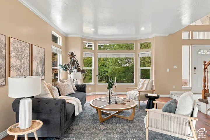 Living area featuring a bay window, wood-finish flooring, vaulted ceilings, recessed lighting, and a staircase with a wooden banister