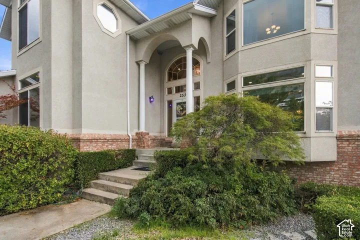 Multi-level exterior featuring a brick and stucco facade, arched entryway with decorative columns, and multi-pane windows