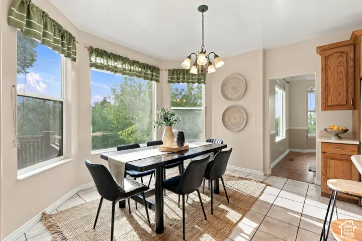 Dining area featuring a bay window, tile flooring, wooden cabinetry, and a multi-arm chandelier