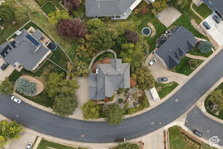 Aerial perspective of a cul-de-sac property featuring a multi-pitched roofline, concrete driveway, mature landscaping, and an attached multi-level rear deck
