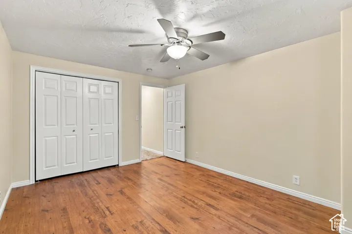 Room featuring wood-finish flooring, a ceiling fan with integrated lighting, and a bifold door closet