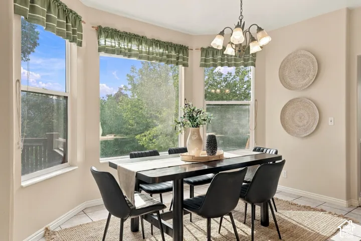 Bay window with multiple windows, neutral wall palette, ceramic tile flooring, and multi-arm chandelier