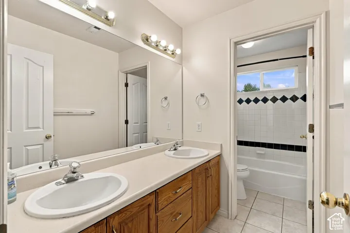 Double vanity featuring wood cabinetry, solid-surface countertops, recessed oval sinks, and a full-width wall mirror
