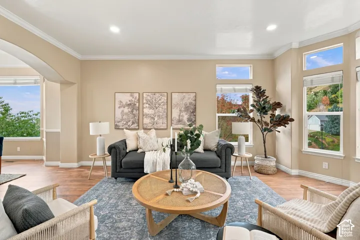 Living area featuring wood-finish flooring, recessed lighting, crown molding, and large windows with natural scenery