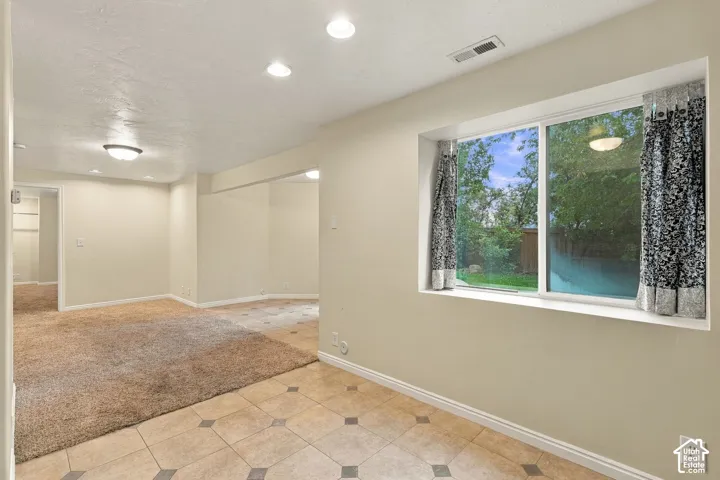 Interior space featuring recessed lighting, large picture window, neutral wall paint, and combination of tiled and carpeted flooring