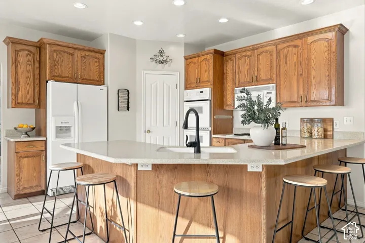 Kitchen featuring wood cabinetry, a peninsula with a stone-finish countertop, a drop-in sink with a matte black faucet, and recessed lighting