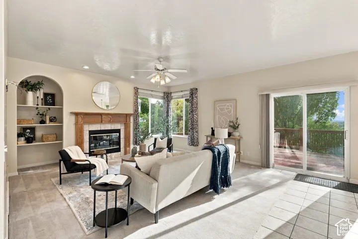 Living area featuring a tile-surround fireplace with a wood mantel, arched built-in shelving, recessed lighting, and glass sliding doors
