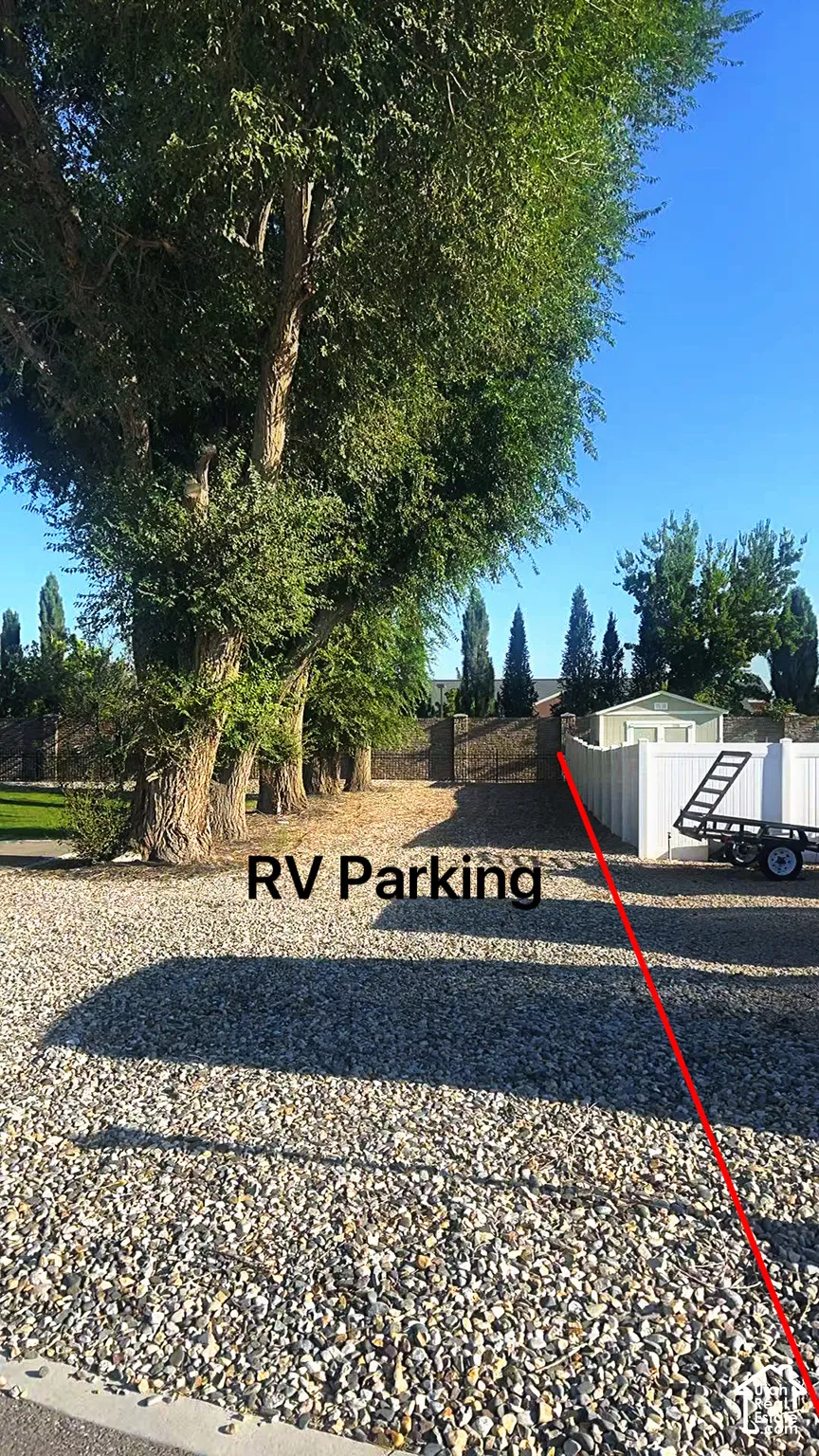 Dedicated RV parking area featuring a generous gravel lot with mature tree-lined perimeter, providing ample space and natural shade