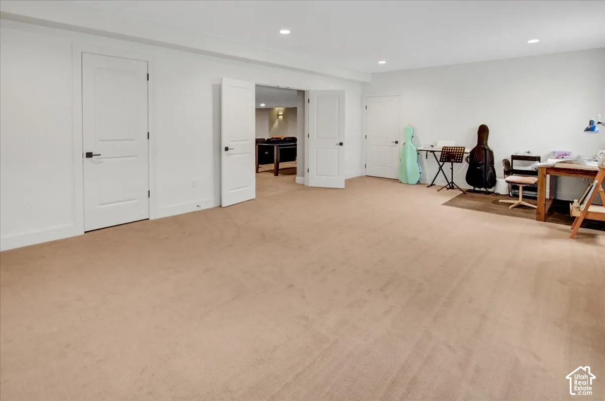 Expansive carpeted area with recessed lighting and neutral wall tones