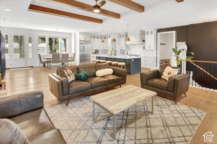 Open-concept interior featuring wood-finish flooring, exposed ceiling beams, and a modern kitchen with a large island