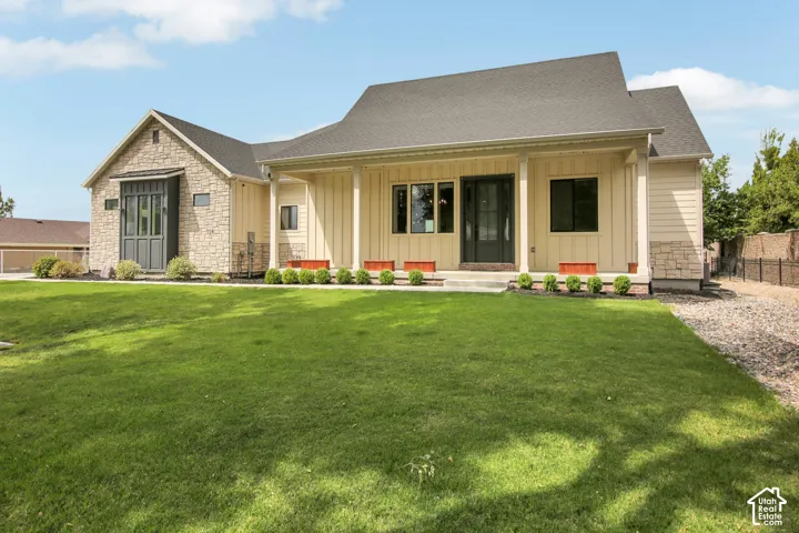 Stone and siding exterior with a covered entry, dark-framed windows, and a dark asphalt shingle roof