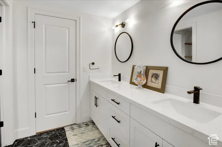 Dual vanity with integrated sinks, white cabinetry, matte black hardware, and hexagonal floor tiling