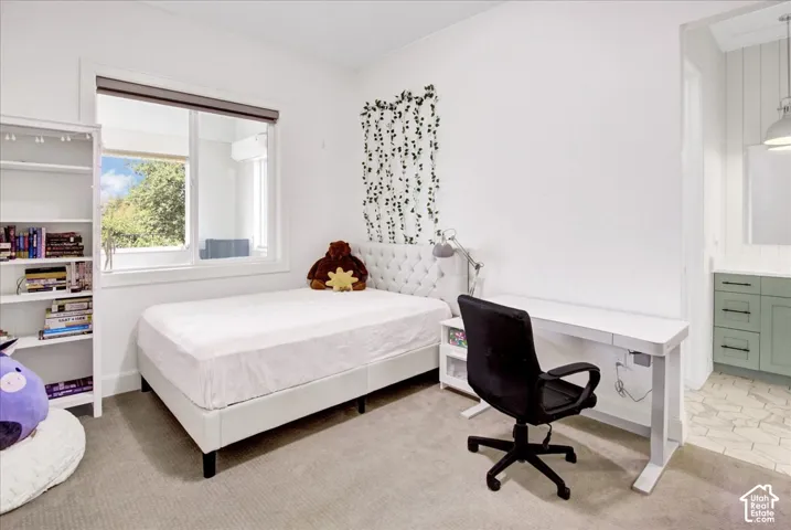 Recessed window with exterior scenery, white built-in shelving, light gray carpeting, and a white built-in desk