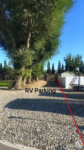 Dedicated RV parking area featuring a generous gravel lot with mature tree-lined perimeter, providing ample space and natural shade