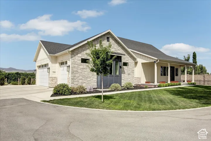 Stone and board-and-batten exterior with a covered front porch and a two-car garage