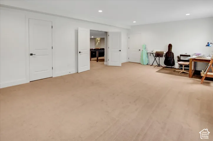 Expansive carpeted area with recessed lighting and neutral wall tones