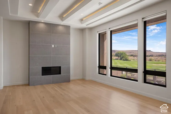 Living space featuring wood-finish flooring, a coffered ceiling with recessed lighting, and a floor-to-ceiling tile fireplace surround