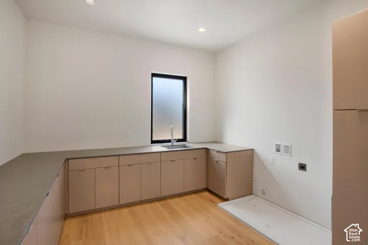 Utility room featuring flat-panel cabinetry, solid-surface countertops, an undermount sink with a gooseneck faucet, and wood-finish flooring