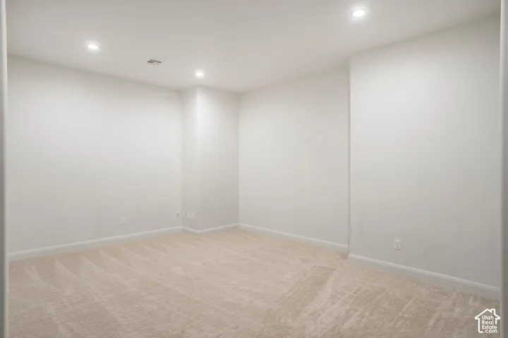 Neutral interior space featuring high-pile wall-to-wall carpeting, crisp white walls, and recessed ceiling lighting