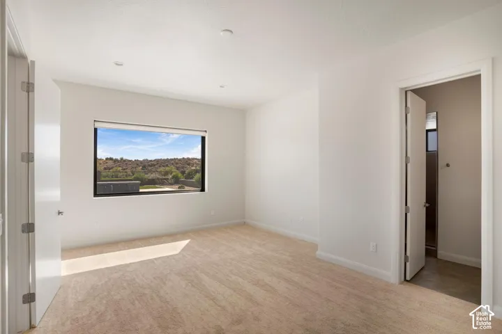 Room featuring neutral-toned carpeting, recessed lighting, and a large picture window showcasing a mountain landscape