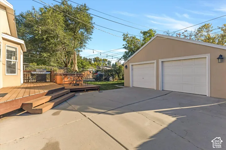 Two-car detached garage with a concrete driveway, elevated wood deck, and chain-link fencing