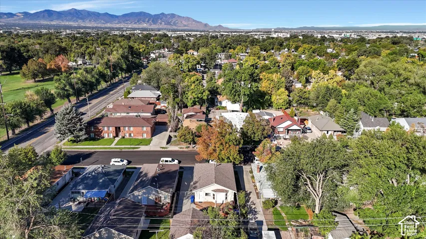 Aerial perspective featuring an established neighborhood with mature trees and a prominent mountain range backdrop