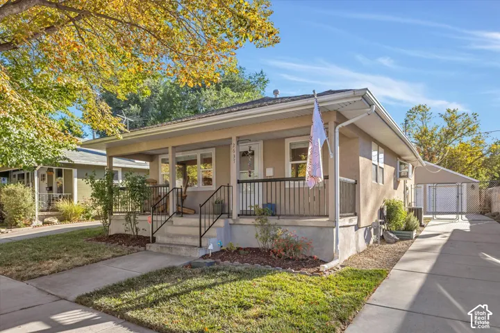 Exterior featuring a covered front porch, stucco siding, metal railing, concrete driveway, and a detached garage