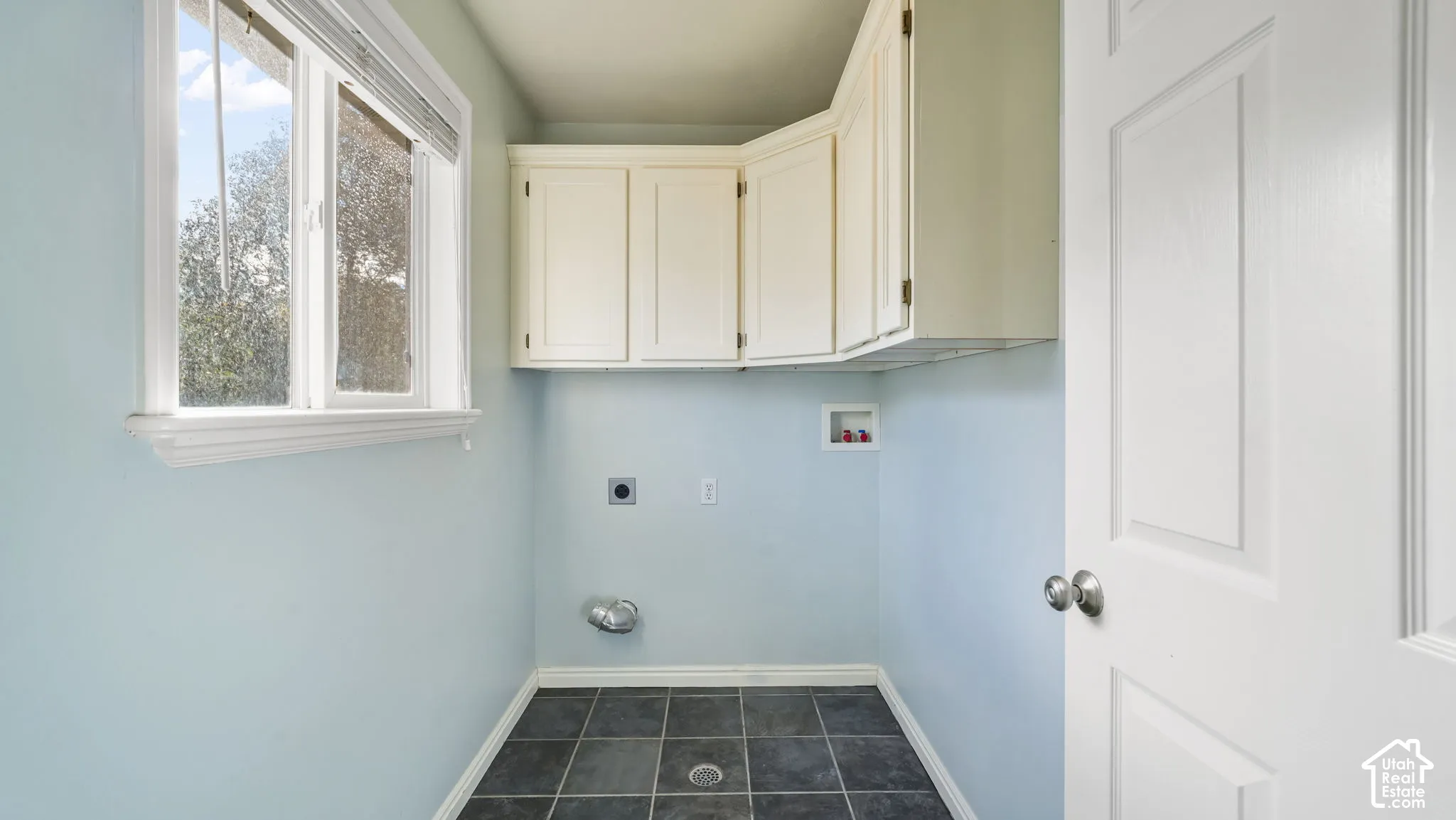 Laundry room with tile flooring and cabinets
