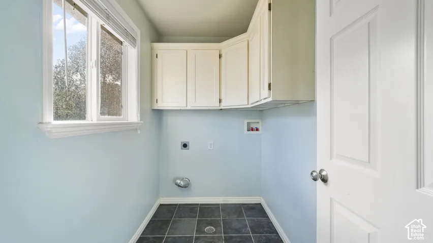 Laundry room with tile flooring and cabinets