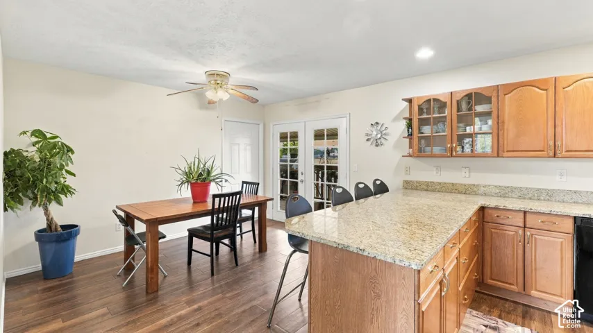 Kitchen featuring wood-finish cabinetry, stone-surface countertops, an integrated peninsula, wood-finish flooring, and glass-paneled double doors