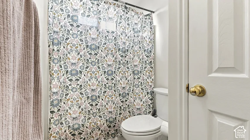 White bathroom featuring a porcelain toilet and a panel door with brass-finish hardware