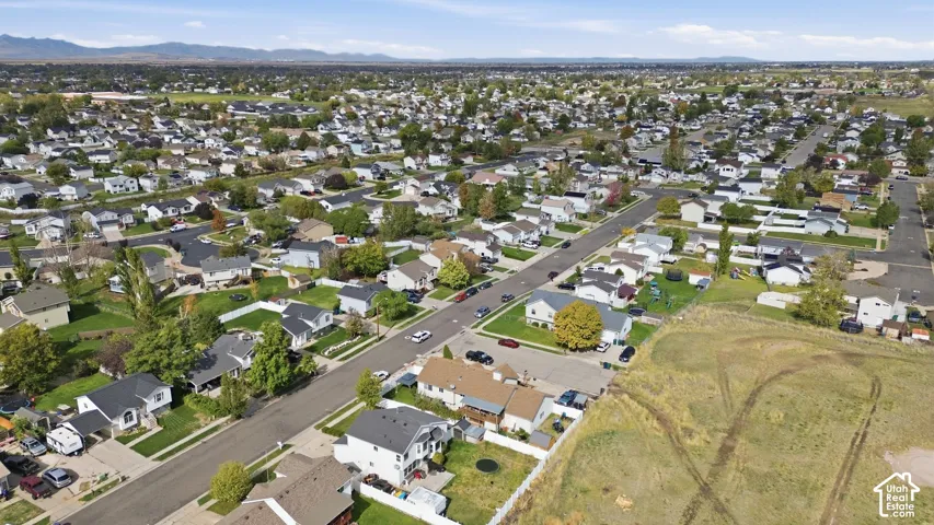 Aerial perspective of residential neighborhood featuring mature trees, paved streets, and a backdrop of mountain ranges